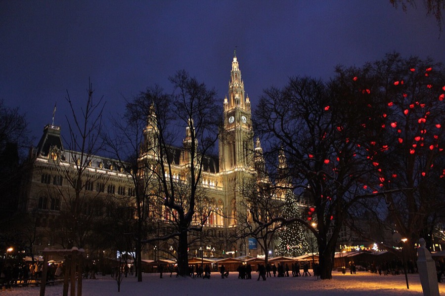 Vienna's floodlit Rathaus above the snowy Christmas market at dusk